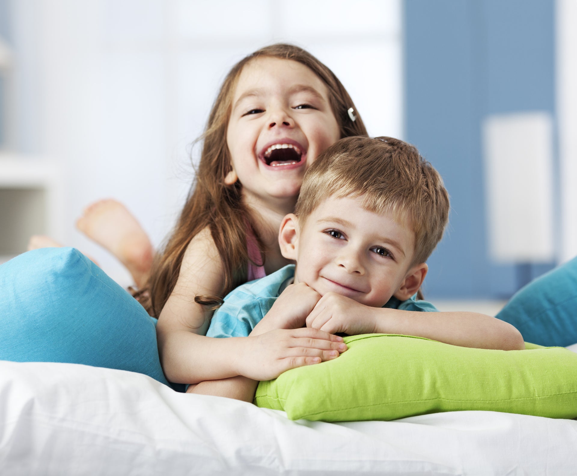 Portrait of two smiling siblings lying on cushions